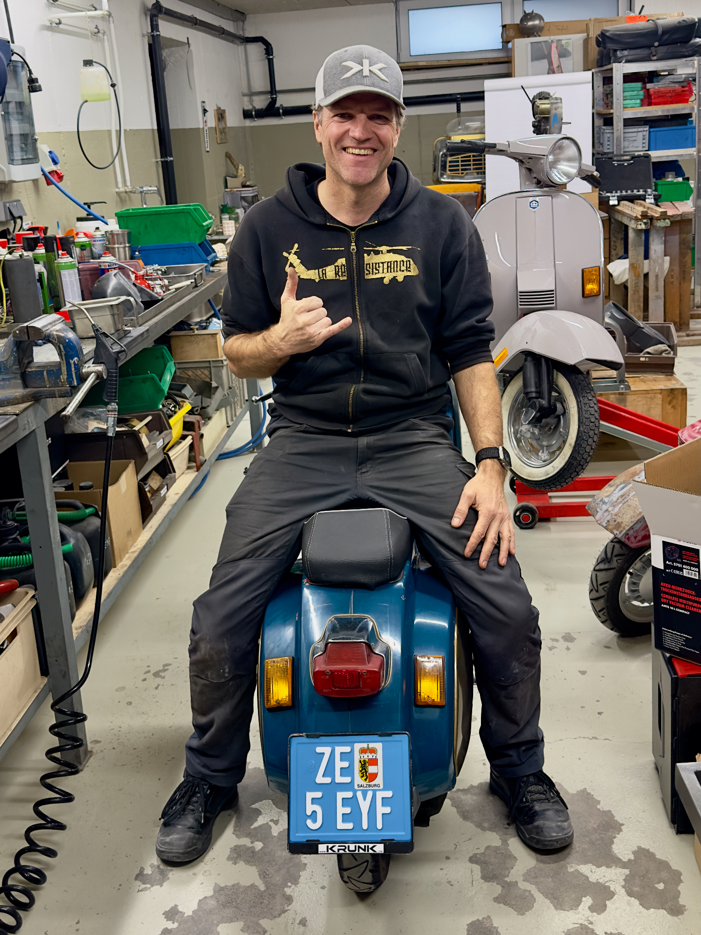 Gerhard auf seiner Vespa in der Werkstatt mit Hang-Loose-Gruß